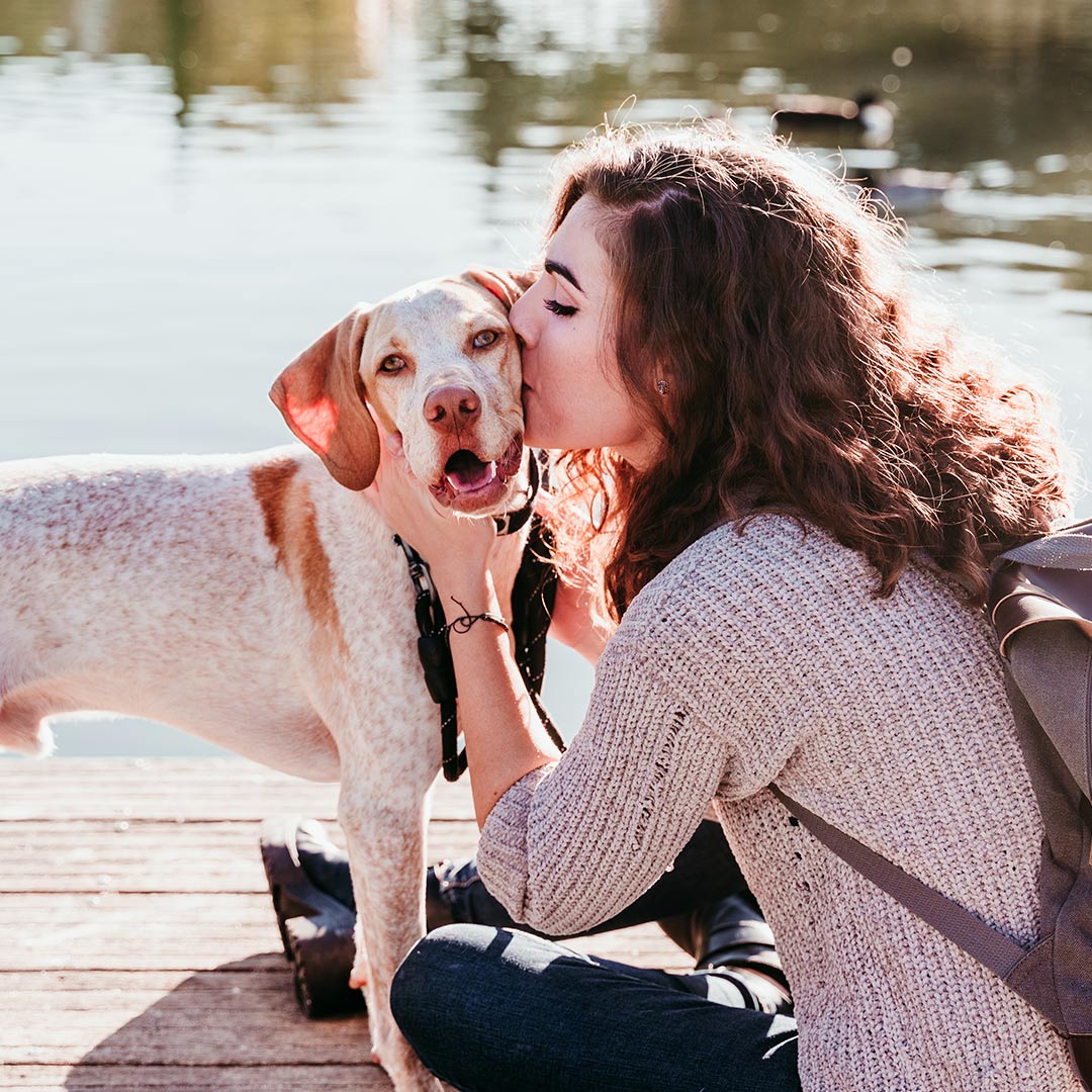 Woman carrying gray cat indoors.